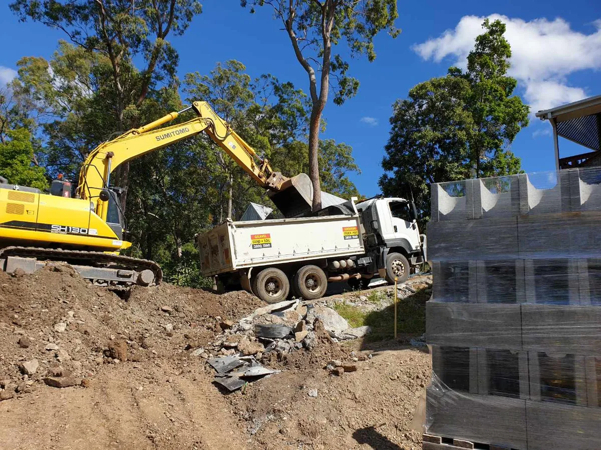 An excavator loading a Leighton tipper truck on site